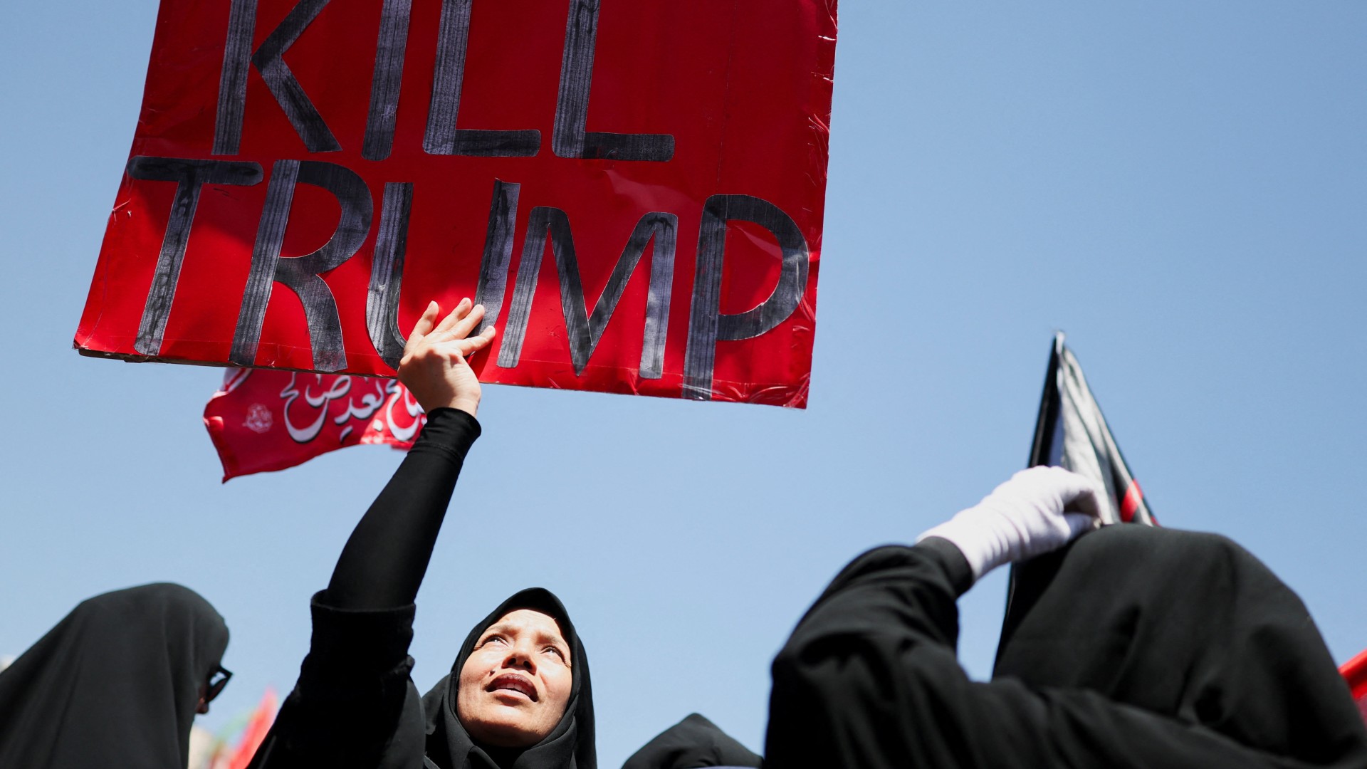 A woman holds an anti-Trump sign as mourners gather during Khamenei’s burial ceremony in Mashhad, Iran, 9 July 2026 (Mohammed Salem/Reuters)