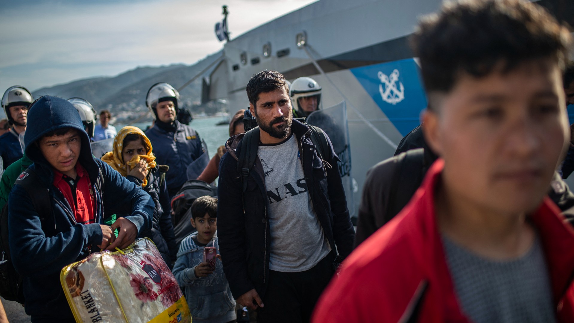 Riots police push back migrants outside the port of Lesbos, on March 3, 2020, amid a migration surge from neighbouring Turkey