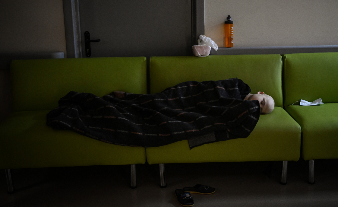 A child struggling with cancer sleeps on a sofa after being evacuated to the basement of the oncology centre which is being used as a bomb shelter in Kyiv on February 28 2022