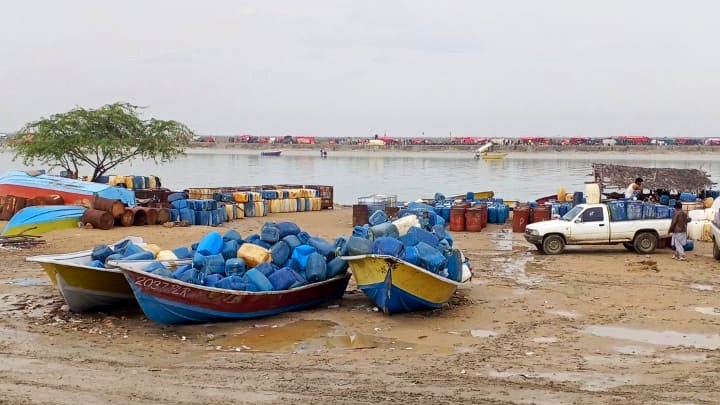 Boats loaded with plastic fuel containers rest along the muddy shoreline at Kuntani Hor 