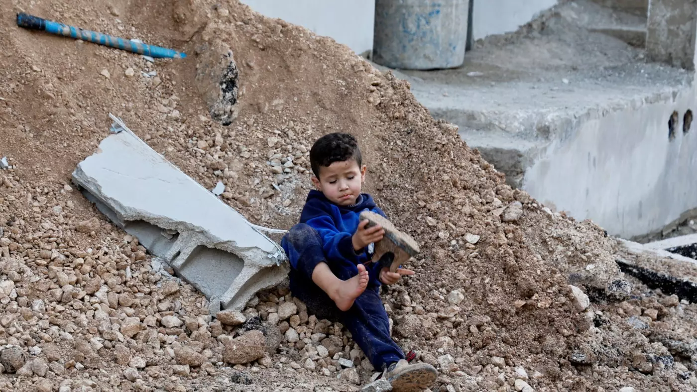 A Palestinian child sits on a street damaged during an Israeli raid in Jenin camp, in the Israeli-occupied West Bank, 21 November 2024 (Raneen Sawafta/Reuters)