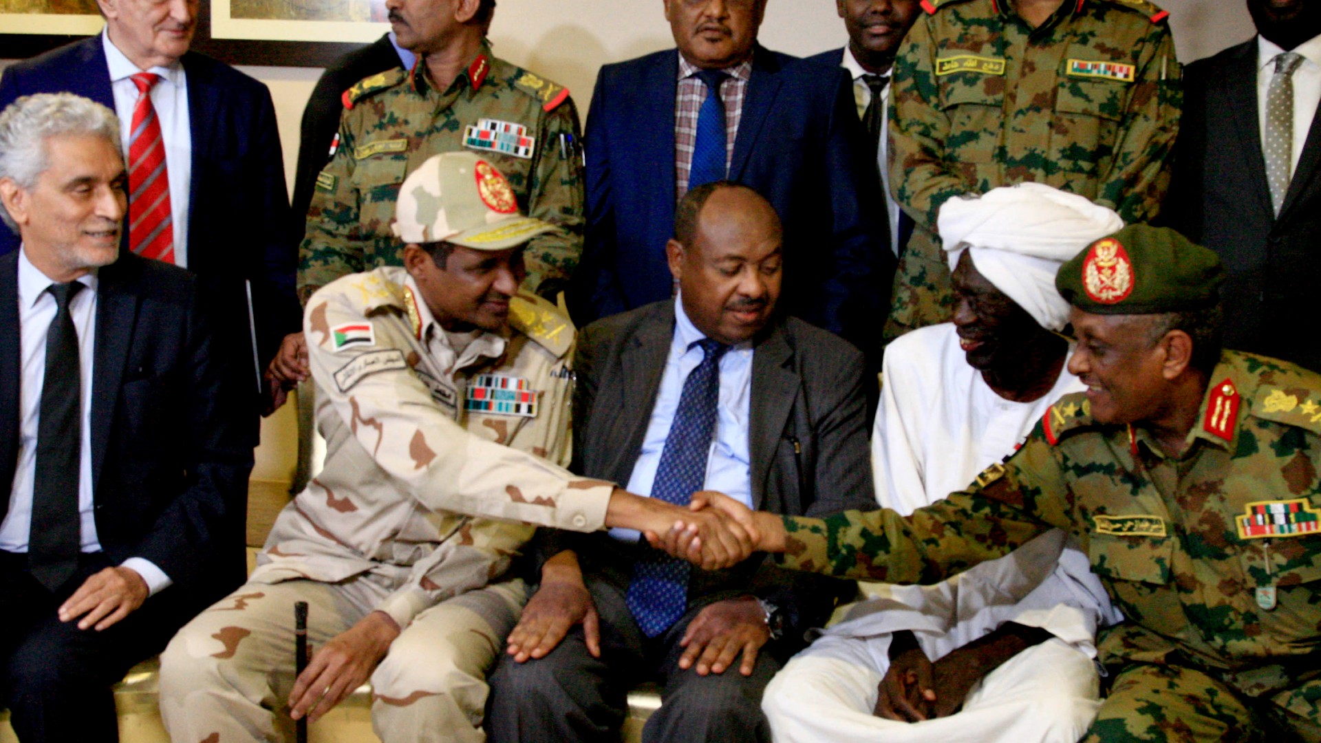 RSF leader Mohammed Hamdan Daglo, aka Hemedti, second left, shakes hands with Yasser al-Atta, right, at a news conference in Khartoum on 5 July 2019 (Ebrahim Hamid/AFP)