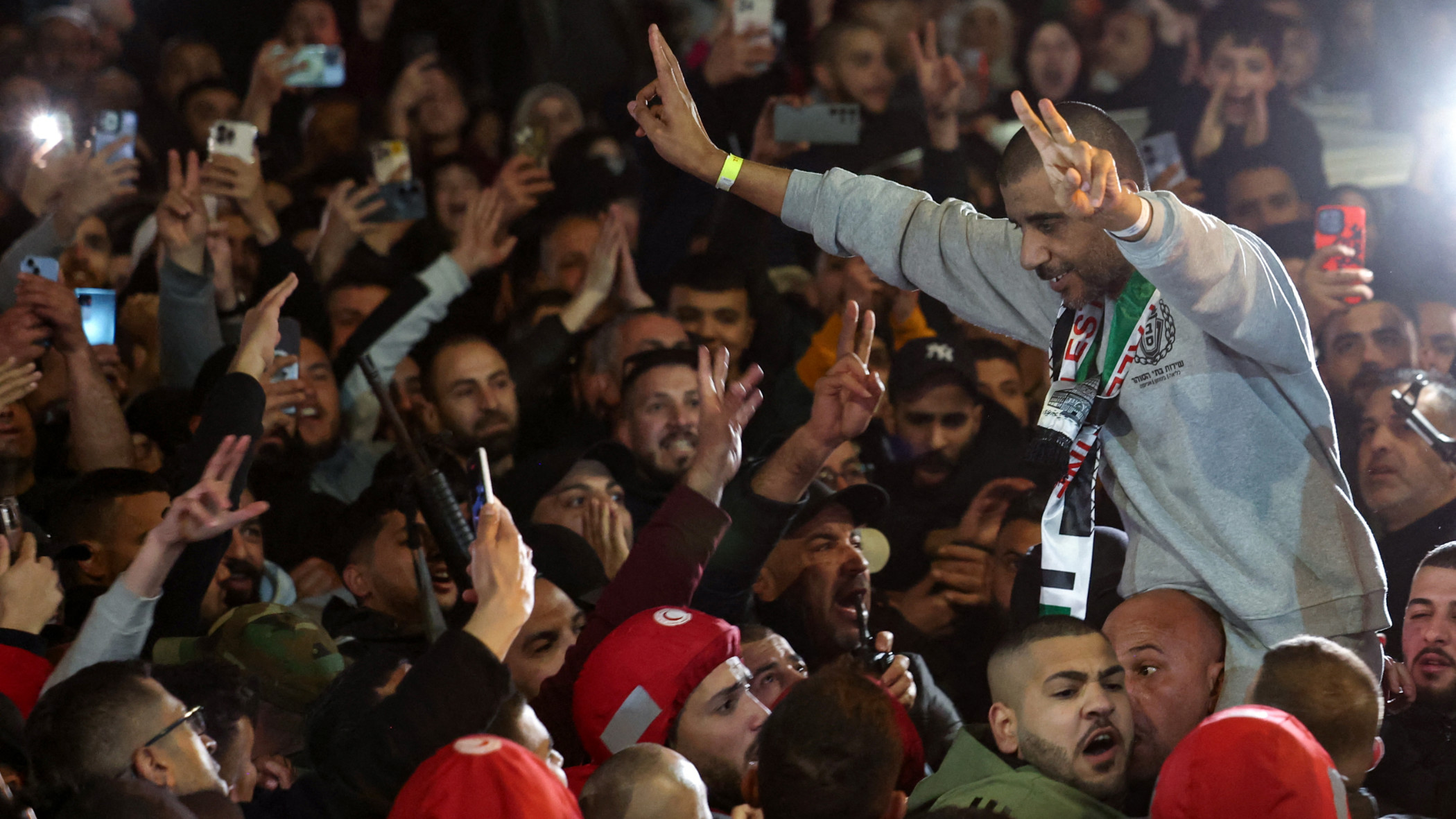 Former Palestinian prisoner Zakaria Zubeidi flashes victory signs as he is lifted by the crowd upon arrival to Ramallah in a Red Cross convoy after their release by Israel on 3 January 2025 (AFP)